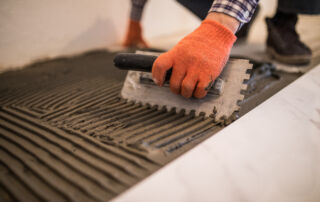 laying ceramic tiles. troweling mortar onto a concrete floor in preparation for laying white floor tile.